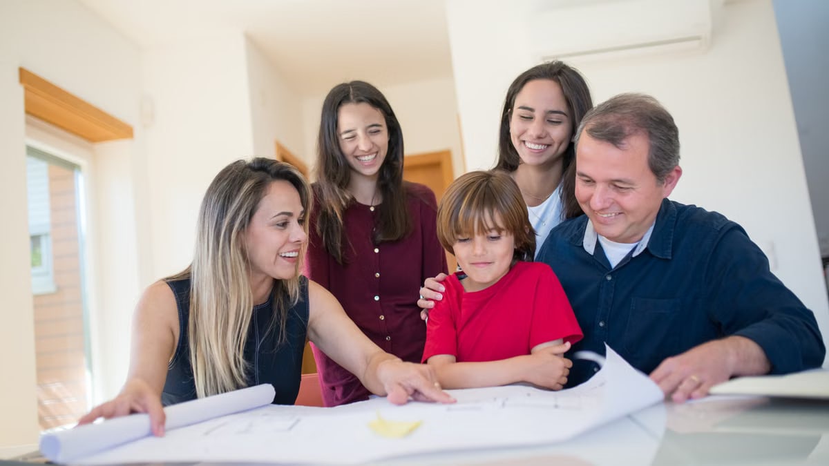 A joyful family gathered around a table reviewing a home blueprint together.